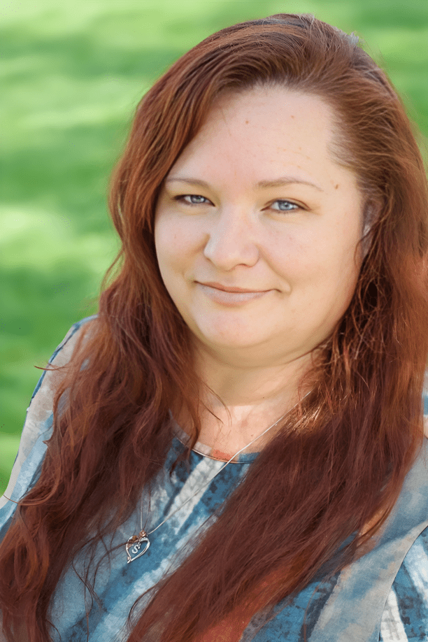 Smiling woman with long red hair outside.